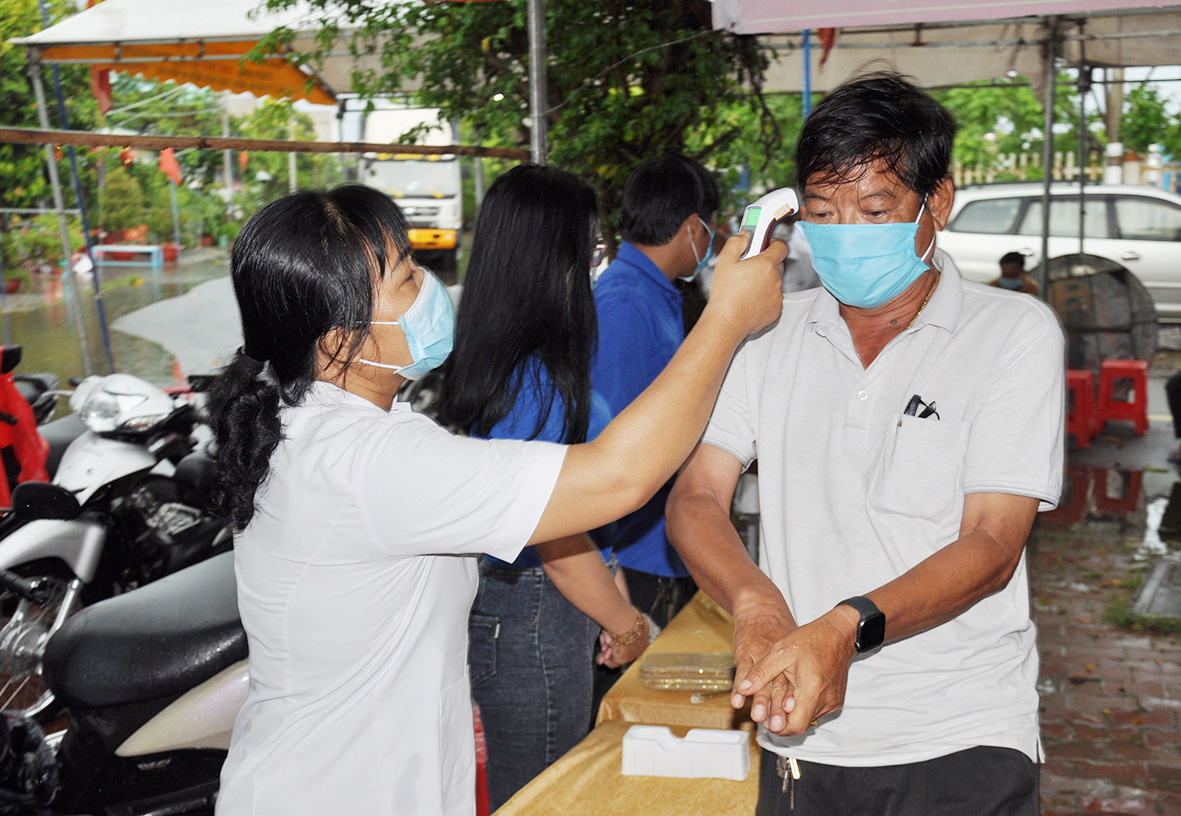 Cử tri thị trấn Kiên Lương (Kiên Lương) được đo thân nhiệt, rửa tay bằng dung dịch sát khuẩn trước khi vào khu vực bỏ phiếu. Ảnh: VĂN PHỤNG